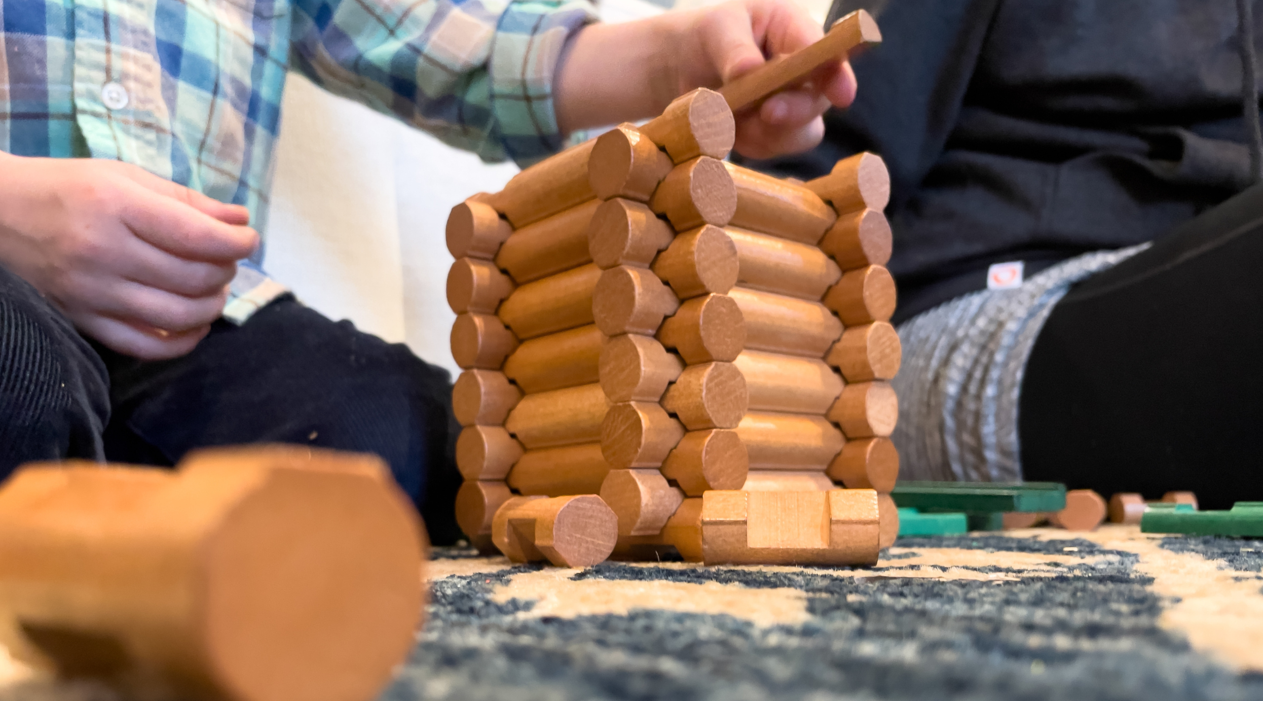 A photo of Lincoln Logs in the process of being stacked, one on top of the other.